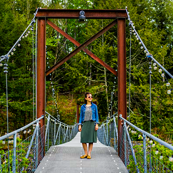 Becca of Half Half Travel stands on a bridge at Antrim Streamside.